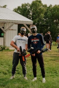 Two guys standing with paintball markers and masks
